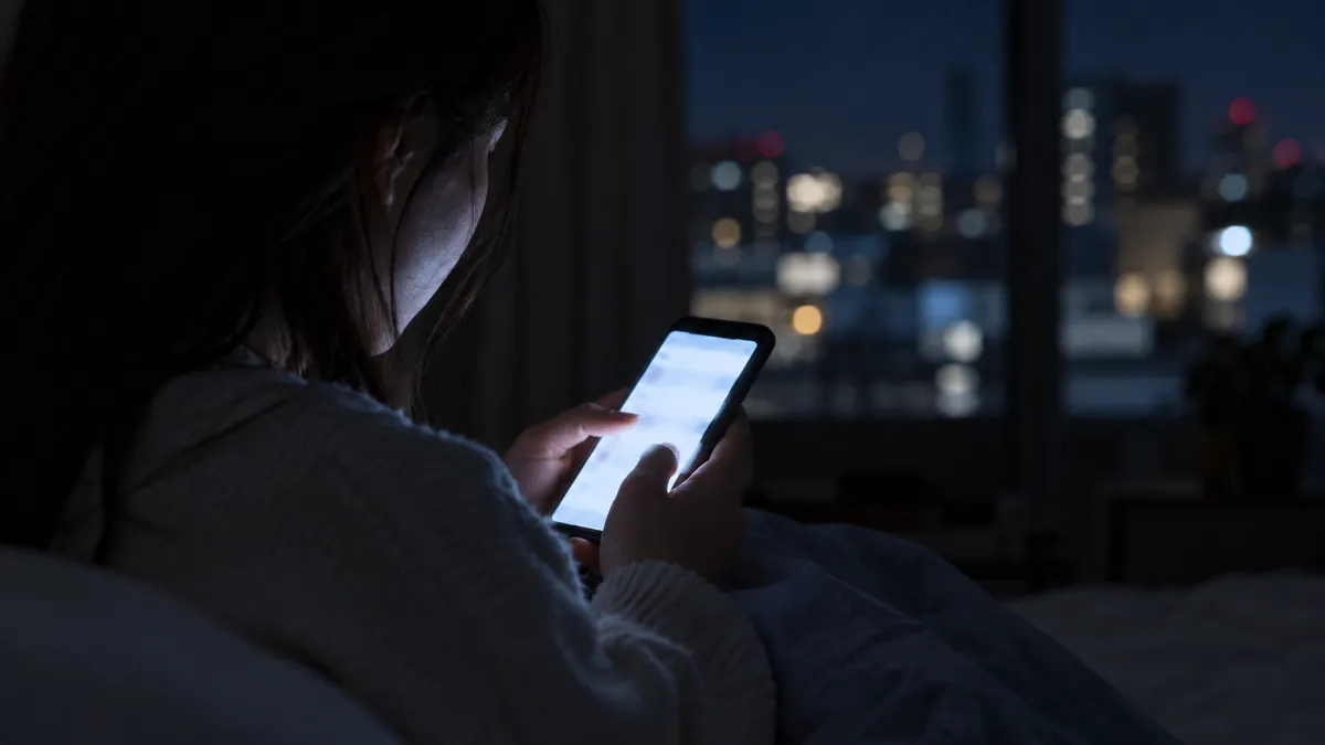 夜、スマートフォンの光に照らされた手元